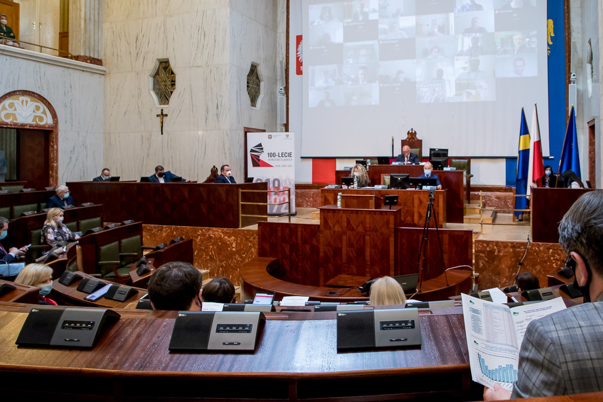 sala Sejmu podczas obrad - prezydium Sejmiku, na ekranie radni biorący udział w sesji zdalnie