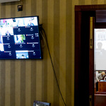 widok ekranu telewizora z podglądem wizerunku radnych biorących udział w sesji zdalnie
