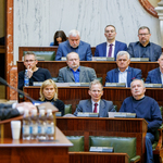 widok kilku ław na sali Sejmu, w których zasiadają ludzie