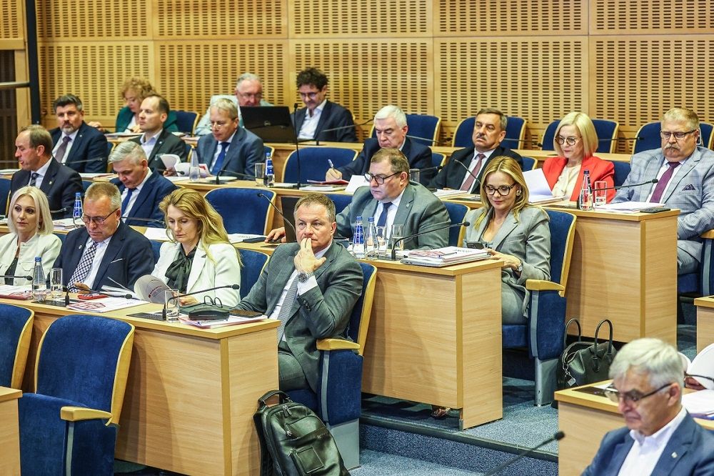 widok sali obrad z oddali, w ławach zasiadają ludzie
