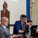 mężczyzna siedzący za biurkiem przemawia