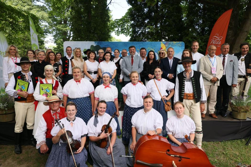 kilkudziesięcioro ludzi w postawie stojącej, wśród nich osoby w strojach góraskich