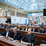 troje mężczyzn siedzi za biurkiem i uczestniczy w obradach