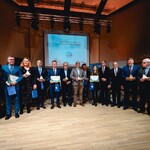 grupa osób w uroczystej postawie stojącej prezentuje statuetki - nagrody