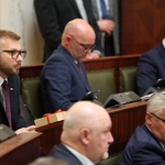kilkoro ludzi zasiada w ławach sejmowych