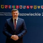 Mężczyzna stoi na tle baneru z napisem Konwent Przewodniczących Sejmików Mazowieckie 2026