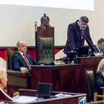 mężczyzna stojący za biurkiem przemawia 